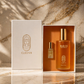 CLEO VII The Ritual Gift Set — presented in an open crème gift box with a gold Cleopatra logo, displayed beside its lid on a marble background. The set includes a frosted glass Royal Seed Elixir Body Oil bottle (100ml / 3.4 oz) and a Jasmine & Orris Roll-On glass Perfume Oil (3ml / 0.10 oz).